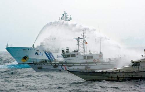 臺(tái)灣“海巡署”的巡邏船（中）在掩護(hù)保釣船“全家?！碧?hào)（右）躲避日本海上保安廳巡視船的水炮攻擊。