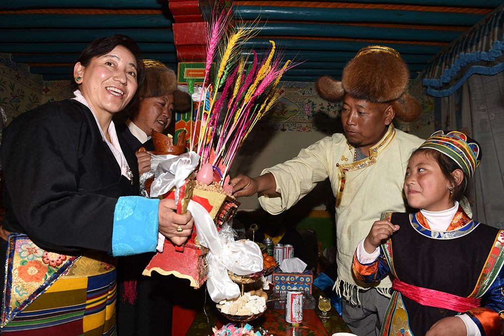 2月27日，拉薩市城關(guān)區(qū)阿壩林卡社區(qū)居民央拉（左）向鄰居敬獻(xiàn)“切瑪”。